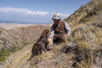 Traditional Kyrgyz eagle hunter hunting with prey, near Kysyl-Suu, Issyk Kul, Kyrgyzstan, Asia