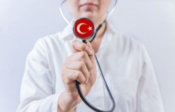 Female doctor holding stethoscope with Turkish flag. Turkiye Health and Care concept