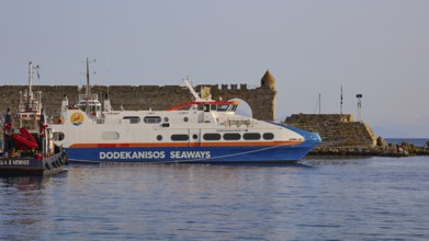 A white ferry lies in front of an old coastal fortification in the calm sea, De Naillac Tower,