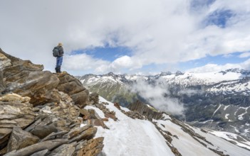 Mountaineer on a rocky ridge with snow, descent from the summit of Schönbichler Horn, view of