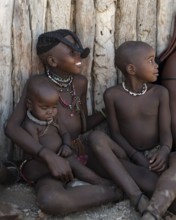 Himba boy and Himba girl with forward braided plaits with baby, near Opuwo, Kaokoveld, Kunene,