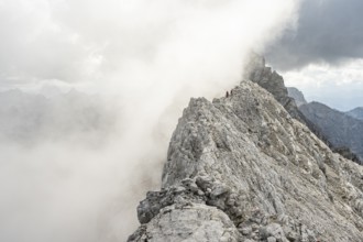 Clouds move around narrow rocky mountain ridge with mountaineers, Watzmann crossing to Watzmann