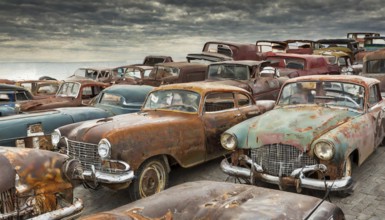 Row of abandoned, rusted cars in a large junkyard under a cloudy sky, symbolic photo, AI generated,