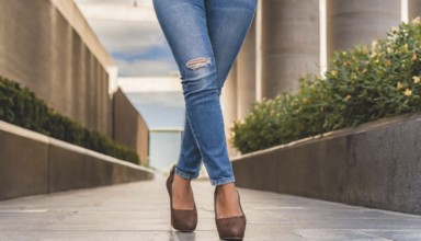 A person in jeans and brown high heels stands in a modern urban environment on a sunny day, AI