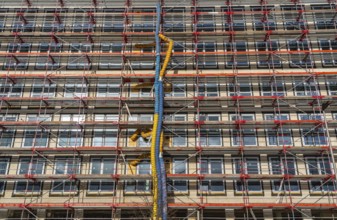 Large construction site, scaffolded shell of an office building complex, air hoses for building