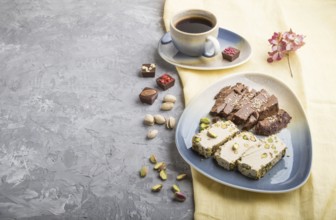 Traditional arabic sweets sesame halva with chocolate and pistachio and a cup of coffee on a gray