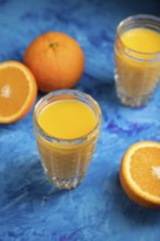 Glass of orange juice on a black and blue background. Hard light, contrast. Side view, close up