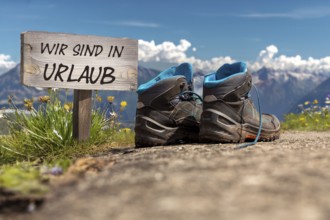 Symbolic image of company holidays/summer holidays: Hiking boots in front of an alpine backdrop and