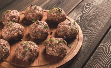 Raw meatballs, with micro greenery, on a cutting board, homemade, rustic, no people