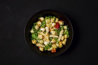 Fresh traditional Caesar salad, with chicken, on a black background, Top view, dark background,