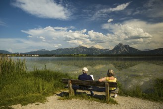 Elderly couple, pensioner, park bench, Hopfensee, near Fuessen, behind them the Ammergau Alps,