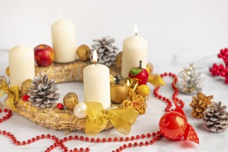 Advent wreath with two burning candles, red pearl necklace and Christmas decorations next to it