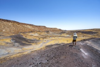 Tourist enjoying the view on a hill, Dry landscape with yellow grass and black volcanic hills,