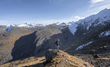 Mountaineer standing on a rock, surrounded by an impressive mountain landscape with snow-covered