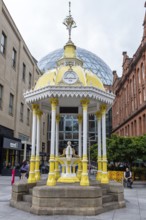 Yellow historic pavilion in a public square surrounded by old buildings, Belfast