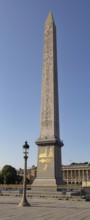 Towering obelisk with ancient symbols, next to a street lamp, Paris