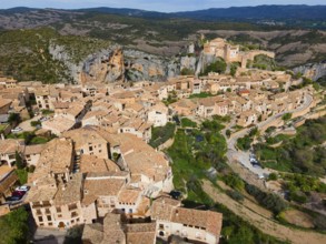 A picturesque medieval village with tiled roofs in a mountainous landscape, aerial view, collegiate