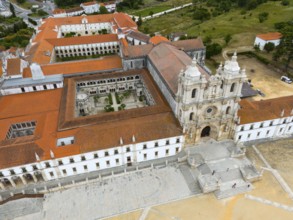 Historic monastery with red roof and courtyard, surrounded by landscape, aerial view, Mosteiro de