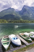 Jetty with boats at Hintersee, with green mountains in the background, peaceful and idyllic natural