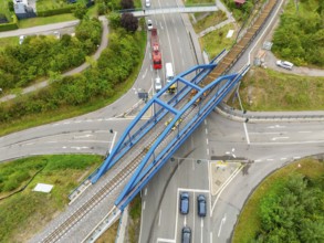 Aerial view of road and rail crossing with blue bridge scaffolding, track construction, rail