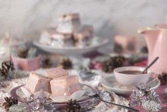 Pink glazed cakes, punch doughnuts surrounded by winter decorations, coffee pot and cup of coffee