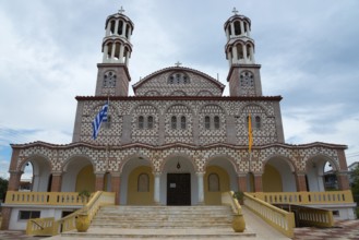 Imposing church with two towers and flags against a cloudy sky, Church of Agios Georgios, Nea