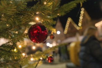 Red Christmas baubles and lights decorate a tree at night, Christmas market Nagold, Black Forest,