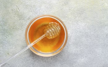 Spoon with honey, on the table, spindle for honey, close-up, rustic view