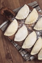 Traditional Polish dish, dumplings, raw, frozen, on a cutting board, wooden table, top view, no