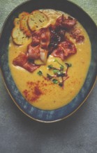 Pumpkin cream soup, curry, fried bacon, bruschetta chips, micro-greens, top view, no people