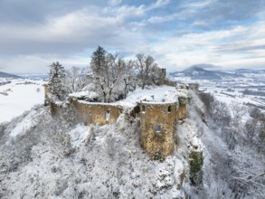 Aerial view of the snow-covered Hegau volcano Mägdeberg with remains of a castle wall on a cold