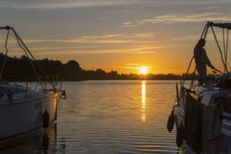 Boats on a lake at sunset with calm water surface, woman fishing, Lake Ilinsk, Jelonek, Milomlyn,