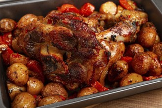 Pork knuckle, baked with vegetables, new potatoes, on a baking sheet, homemade, no people