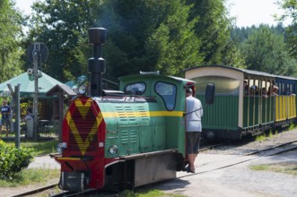 A train with people in the wagon stands at a small, rural railway station, diesel locomotive, Wls