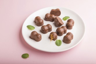 Chocolate caramel candies on a pastel pink background. Side view, close up