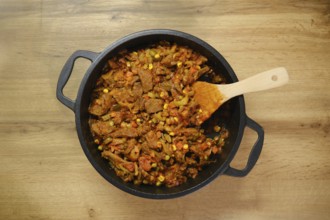 Overhead view of beef and vegetables ragout on wooden countertop in the kitchen