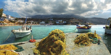 Picturesque bay of the small village of Arkasa with fishing boats and mountains in the background,