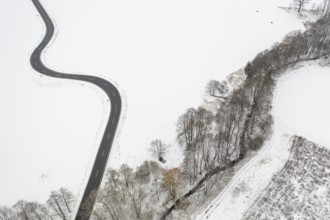 Aerial view of a winding country road and a stream in the snow, between Eppendorf and Leubsdorf,