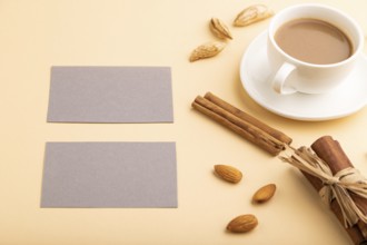 Composition of gray paper business cards, almonds, cinnamon and cup of coffee. mockup on orange