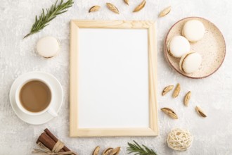 White wooden frame mockup with cup of coffee, almonds and macaroons on gray concrete background.