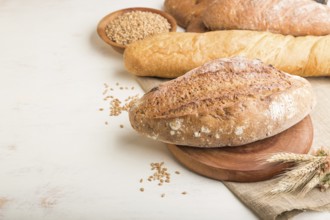 Different kinds of fresh baked bread on a white wooden background. side view, close up, copy space