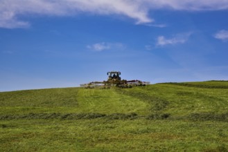 Tractor with hay tedder harvesting hay in the Allgäu in Bavarian Swabia in the Allgäu, Bavaria,