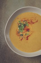 Pumpkin cream soup, in a white bowl on a textured background, top view, homemade, no people, rustic