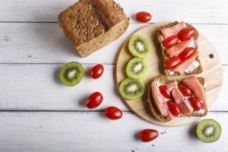 Smoked salmon sandwiches with butter and cherry tomatoes on white wooden background. top view, copy