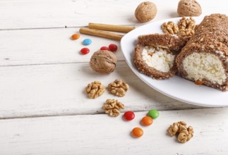 Roll cake with curd and walnuts isolated on white wooden background. close up, copy space