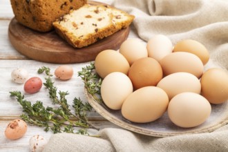 Homemade easter pie with raisins and eggs on plate on a white wooden background and linen textile.