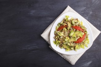 Vegetarian salad of celery, germinated rye, tomatoes and avocado on linen tablecloth, top view,