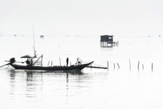 Traditional wooden huts of fishermen in the Gulf of Thailand in the morning haze, fishing boat,