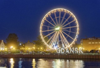 The Ferris wheel illuminated in the evening on the Motlawa, Motlawa, and the lettering Gdansk,