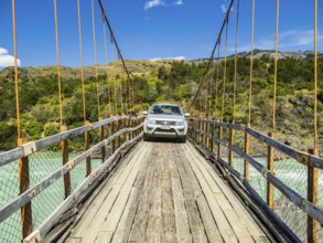 Small car (suv) crossing the river Rio Baker on an old suspension brige, bridge suitable for cars